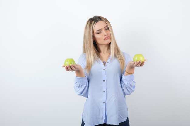 Foto de retrato de una mujer bastante atractiva modelo de pie y sosteniendo manzanas frescas.