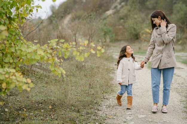 Foto sensual. Pequeña niña bonita. La gente camina afuera. Mujer con un abrigo marrón.