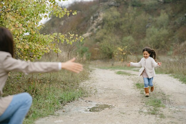 Foto sensual. Pequeña niña bonita. La gente camina afuera. Mujer con un abrigo marrón.