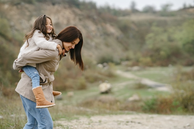 Foto sensual. Pequeña niña bonita. La gente camina afuera. Mujer con un abrigo marrón.