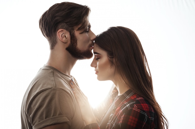 Foto tierna de la joven pareja. Hombre besando a la mujer en la frente.