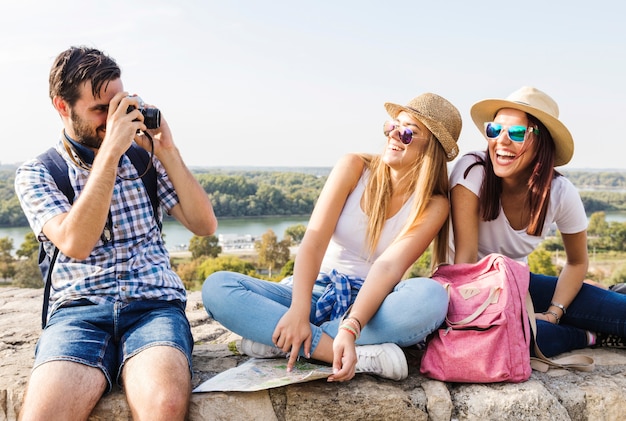 Foto gratuita foto de toma de hombre de dos mujeres de moda felices en cámara