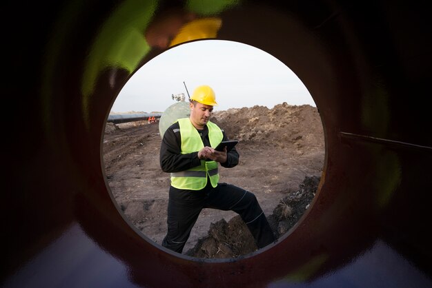 Foto de un trabajador del campo petrolífero comprobando la calidad de las tuberías de gas en el sitio de construcción