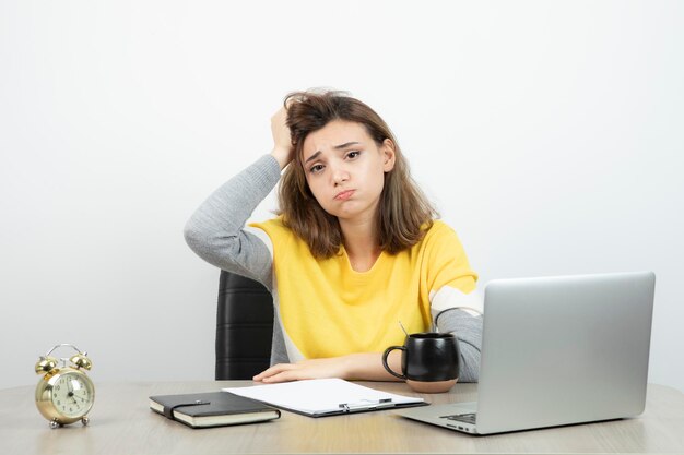 Foto de una trabajadora de oficina sentada en el escritorio con una laptop y un portapapeles. foto de alta calidad