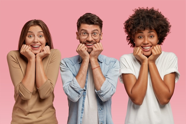 Foto de tres amigos multiétnicos sostienen la barbilla