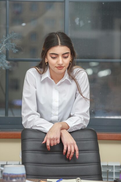 Foto vertical de una chica pensativa en la oficina