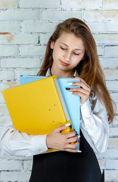 Foto vertical de una estudiante adorable mirando sus cuadernos Foto de alta calidad