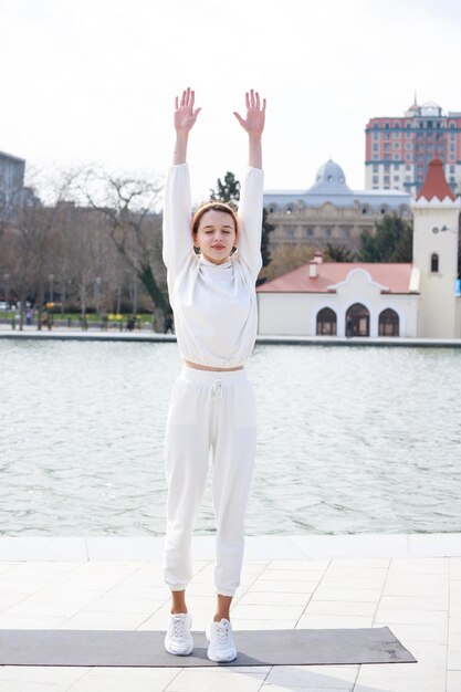 Foto vertical de una joven atleta parada y levantando las manos Foto de alta calidad