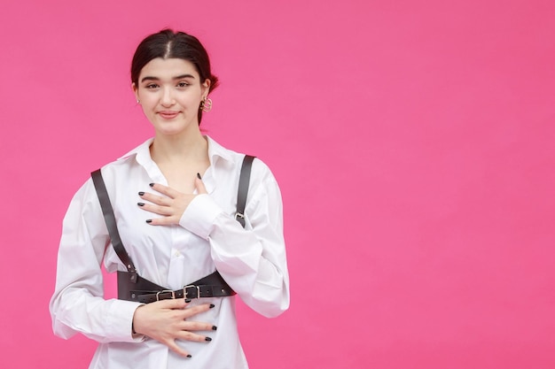 Foto vertical de una joven de fondo rosa sonriendo a la cámara