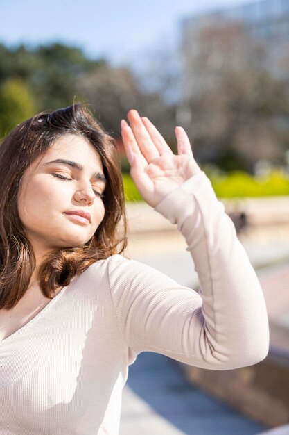 Foto vertical de una joven levantando la mano y cerrando los ojos Foto de alta calidad