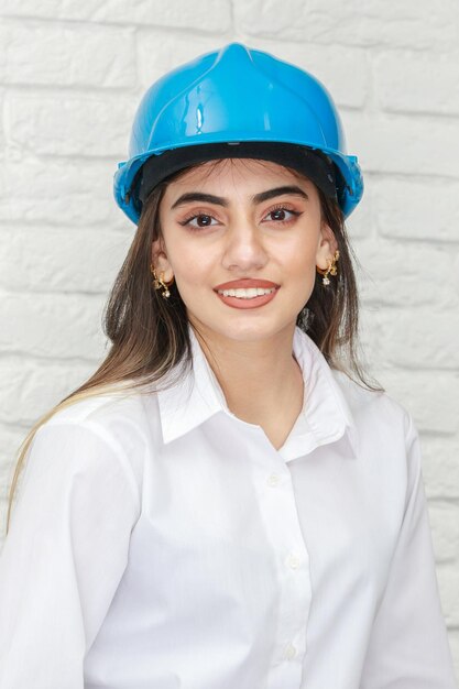 Foto vertical de una joven que lleva un casco de construcción y sonríe a la cámara