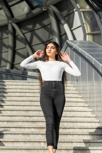 Foto vertical de una joven segura de sí misma en las escaleras de la calle Foto de alta calidad