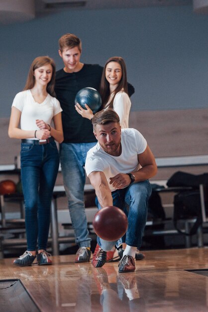 Foto vertical. Jóvenes amigos alegres se divierten en el club de bolos en sus fines de semana