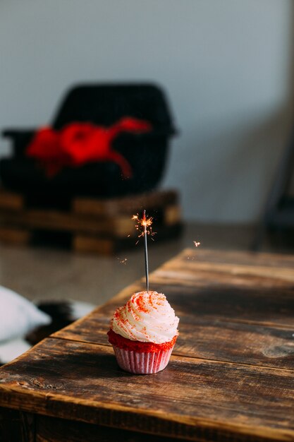 Foto vertical para salvapantallas de smartphone de cupcake rosa terciopelo rojo, con vela de bengala, decorado con glaseado y azúcar