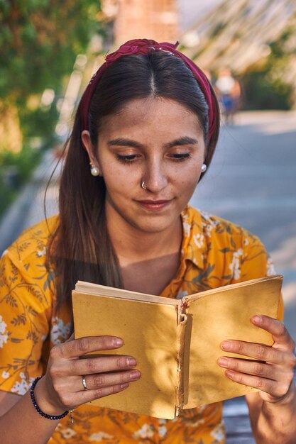 Foto de vista frontal de una niña con una camisa amarilla leyendo un libro