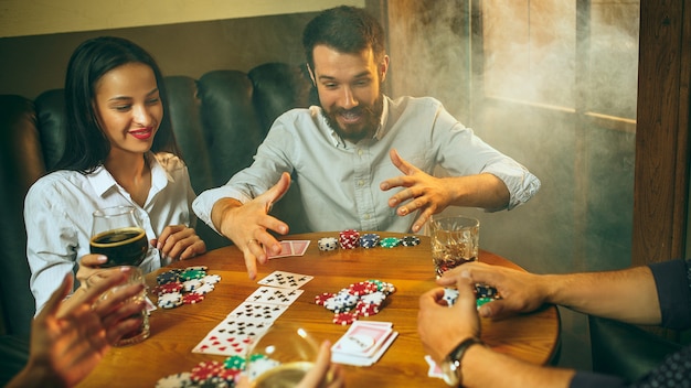 Foto gratuita foto de la vista lateral de los amigos masculinos y femeninos que se sientan en la mesa de madera.