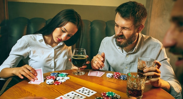 Foto de vista lateral de amigos sentados en la mesa de madera. Amigos que se divierten jugando al juego de mesa.