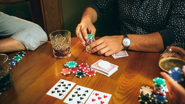 Foto de vista lateral de amigos sentados en la mesa de madera. Amigos que se divierten jugando al juego de mesa.