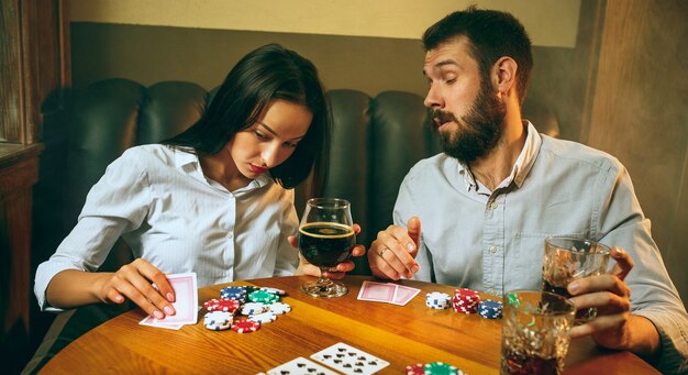 Foto de vista lateral de amigos sentados en la mesa de madera. Amigos que se divierten jugando al juego de mesa.