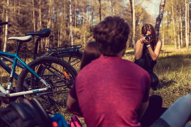 Fotógrafa fotografiando a una pareja deportiva después de andar en bicicleta en el bosque de verano.