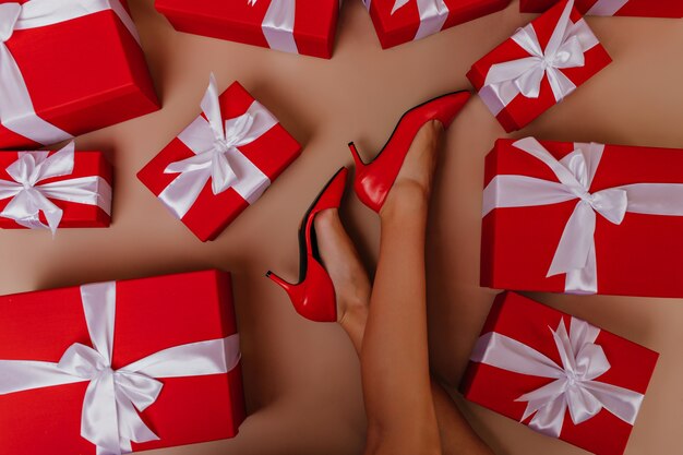 Fotografía aérea de dama delgada acostada al lado de regalos de año nuevo. piernas femeninas en zapatos rojos.