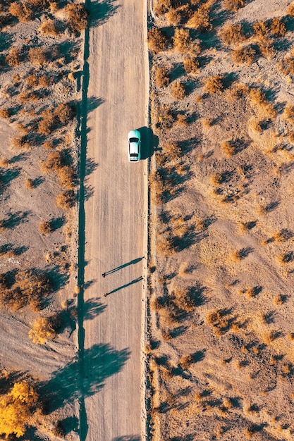 Fotografía aérea de drones aéreos de una estrecha carretera del desierto con un automóvil al costado de la carretera