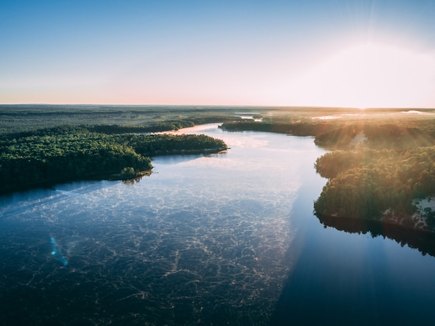 Fotografía aérea de un río rodeado de islas cubiertas de vegetación bajo la luz solar.