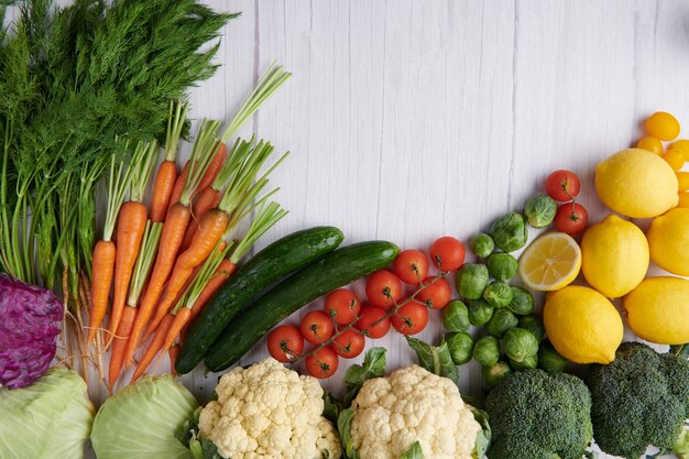 Fotografía de alimentos diferentes frutas y verduras en la superficie de la mesa de madera blanca.