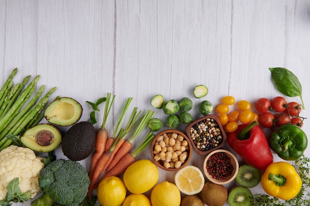Fotografía de alimentos diferentes frutas y verduras en la superficie de la mesa de madera blanca.