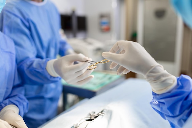 Fotografía de ángulo bajo en la sala de operaciones Asistente entrega instrumentos a los cirujanos durante la operación Los cirujanos realizan la operación Los médicos profesionales realizan la cirugía