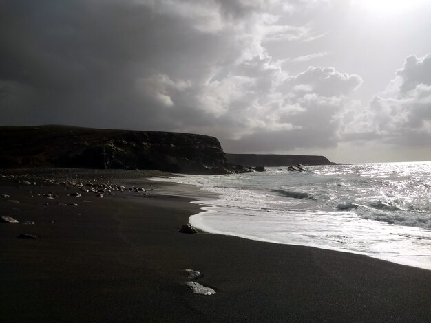 Fotografía en blanco y negro de olas tranquilas en la costa