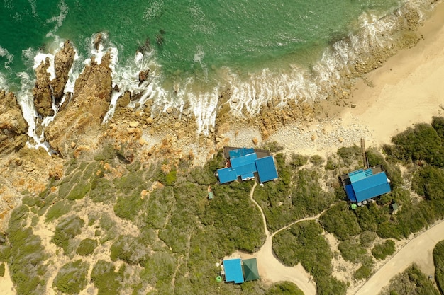 Fotografía cenital aérea de una orilla del mar con agua turquesa pura y cabañas durante el día