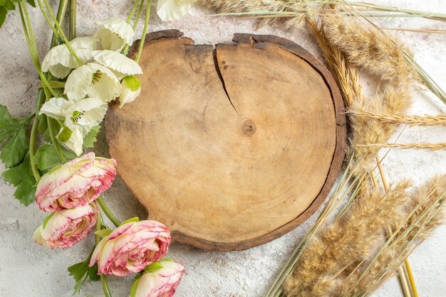 Fotografía cenital de bandeja de madera y emmers y flores a su alrededor en mármol