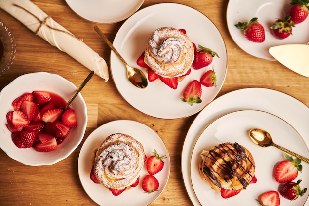 Fotografía cenital de delicioso hojaldre de crema con fresas y chocolate en una mesa de madera