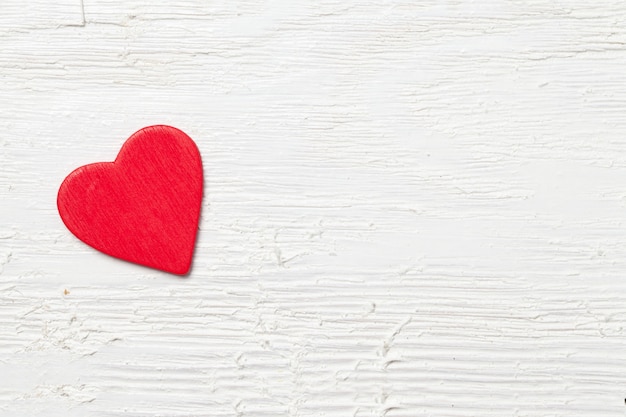 Fotografía cenital de un pequeño corazón rojo sobre un fondo de madera blanca - concepto romántico