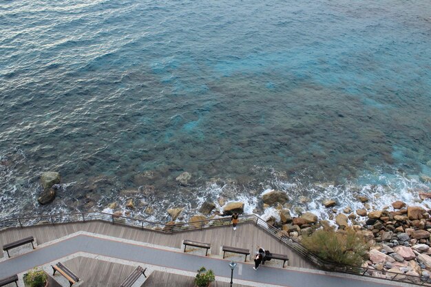 Fotografía cenital de personas tomando una foto cerca de la costa rocosa y un mar