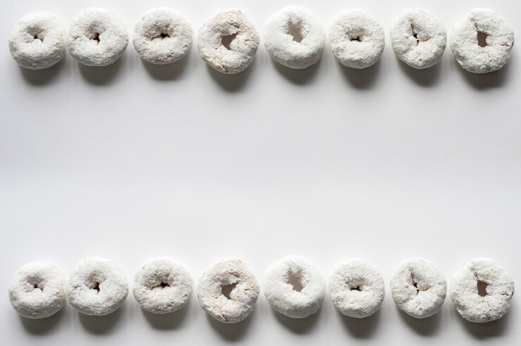 Foto gratuito fotografía cenital de una superficie blanca con donas en el fondo superior e inferior