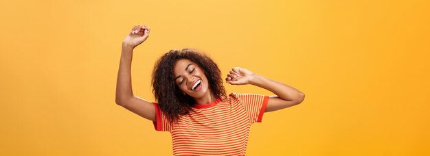 Fotografía de la cintura de una feliz estudiante afroamericana relajada y aliviada en una camiseta a rayas