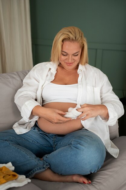 Fotografía completa de una mujer embarazada pasando tiempo en el interior