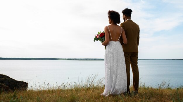 Fotografía completa de la novia y el novio posando al aire libre