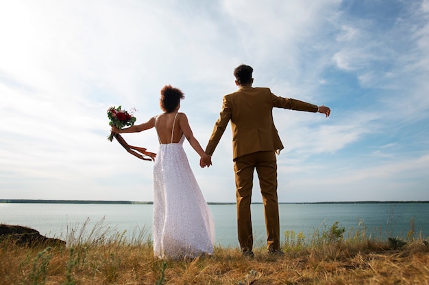 Fotografía completa de la novia y el novio posando al aire libre