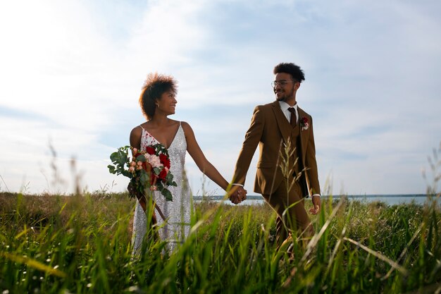 Fotografía completa de la novia y el novio posando al aire libre