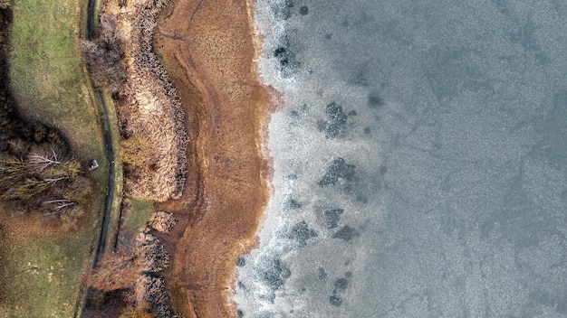 Fotografía de drones de arriba hacia abajo en la orilla del lago congelado día soleado