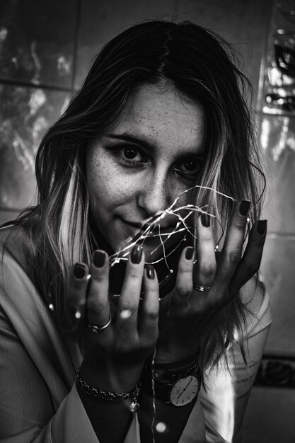 Fotografía en escala de grises de mujer sosteniendo luces de cadena
