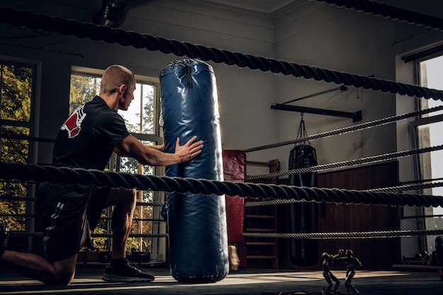 Foto gratuita fotografía oscura de niños entrenando con un gran saco de boxeo en el estudio de boxeo.