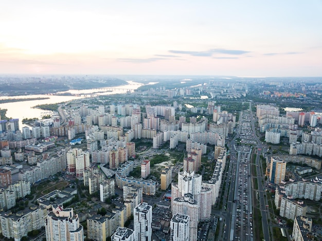 Fotografía panorámica aérea desde la vista de pájaro del dron al distrito de Pozniaky y vista a la orilla derecha del Dnieper con puentes a través de él y el edificio moderno de la ciudad de Kiev