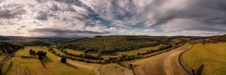 Foto gratuito fotografía panorámica de campos agrícolas bajo la luz del sol y un cielo nublado en el campo