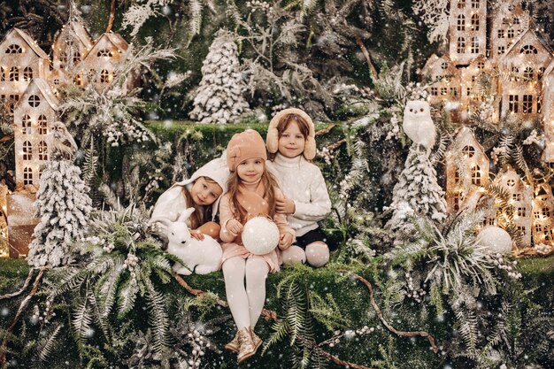 Fotografía de Stock de adorables tres hermanas acurrucarse juntos rodeados de hermosas decoraciones navideñas.