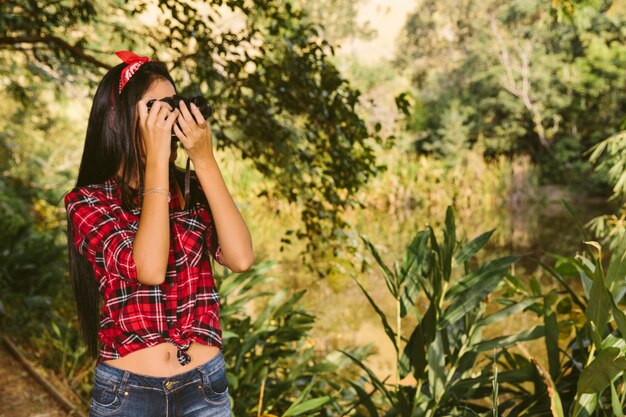 Fotografía de toma de mujer con cámara en el bosque