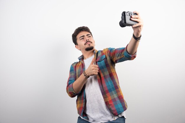 Fotografía tomando sus selfies de manera positiva con una cámara.